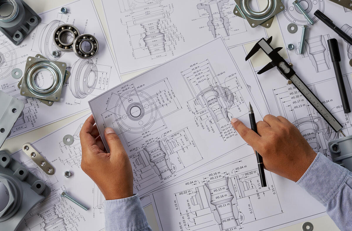 Designer working on mechanical technical drawings with bearings and caliper